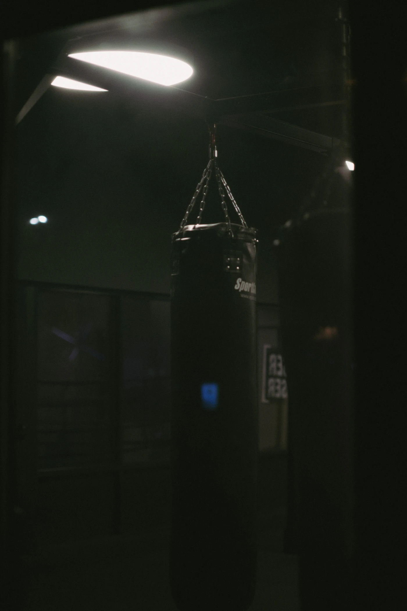A heavy boxing bag hanging in a dark gym