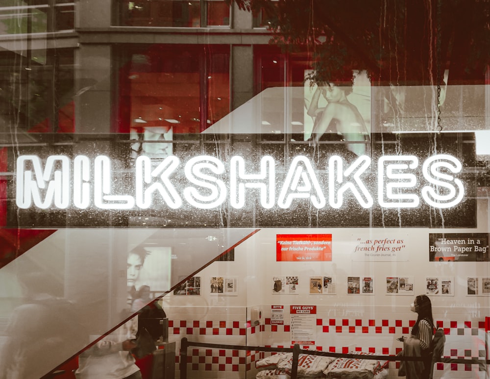 a store window with a neon sign that reads milkshakes