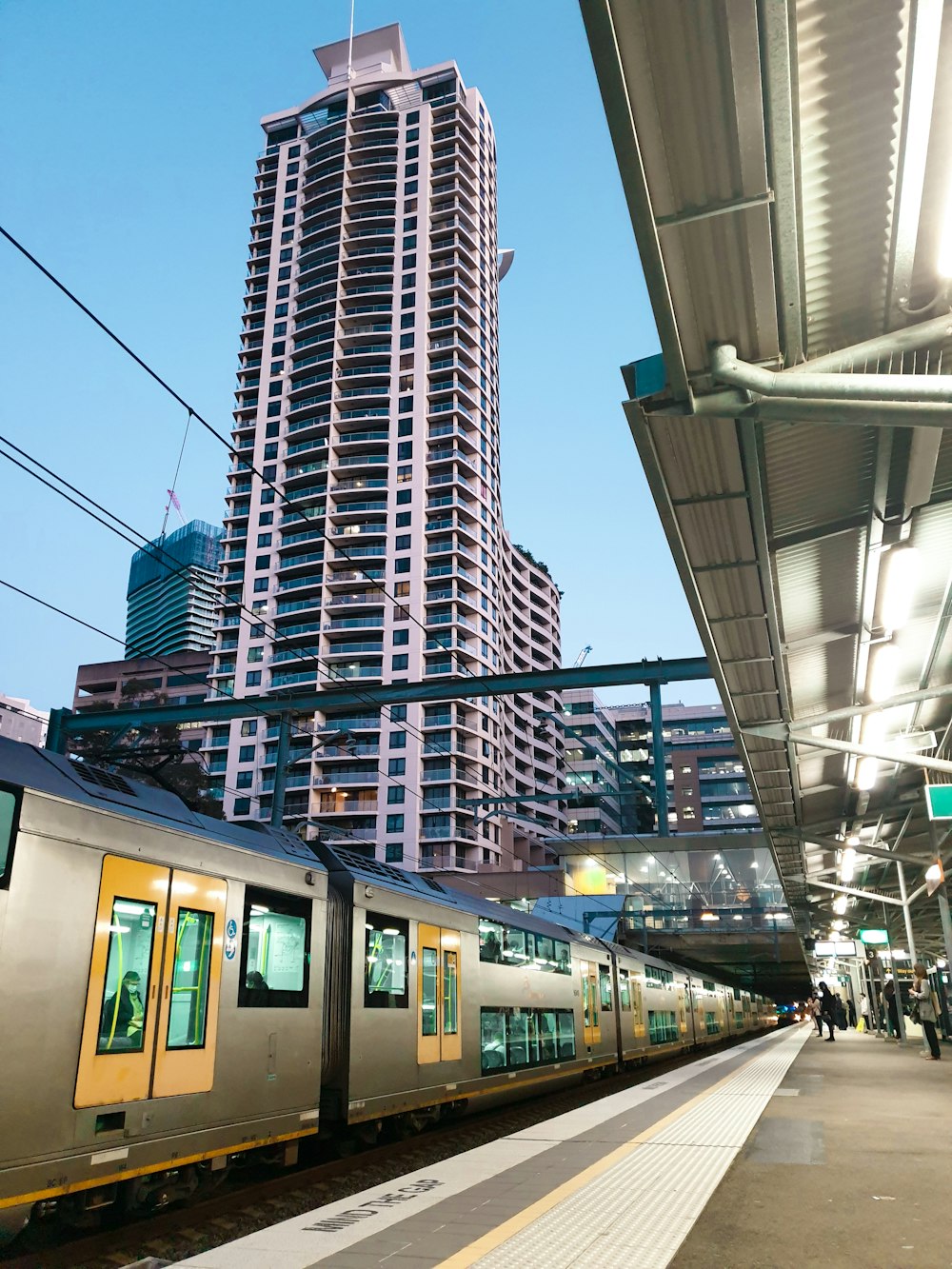 a train pulling into a train station next to a tall building