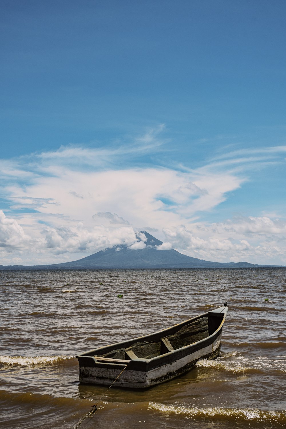 a boat in the water with a mountain in the background