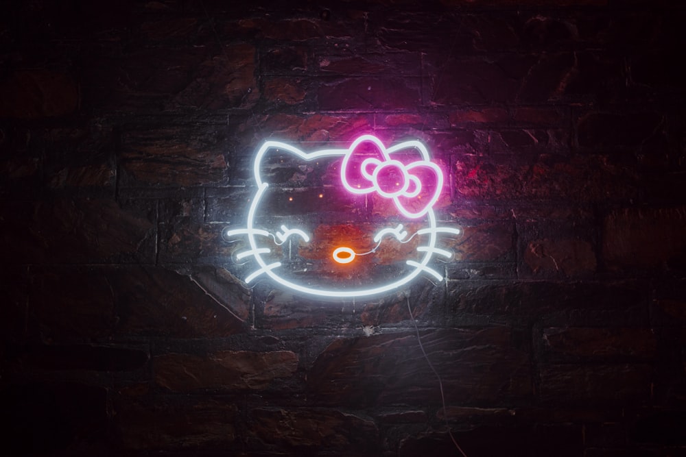 a neon hello kitty sign on a brick wall