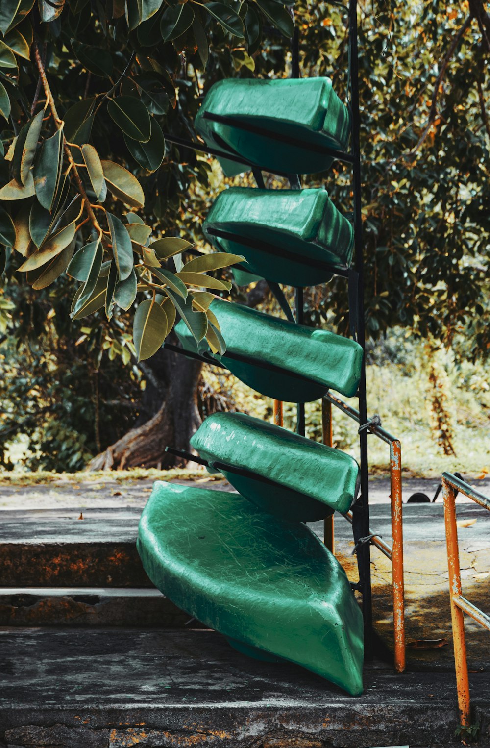 a set of green slides sitting next to a tree