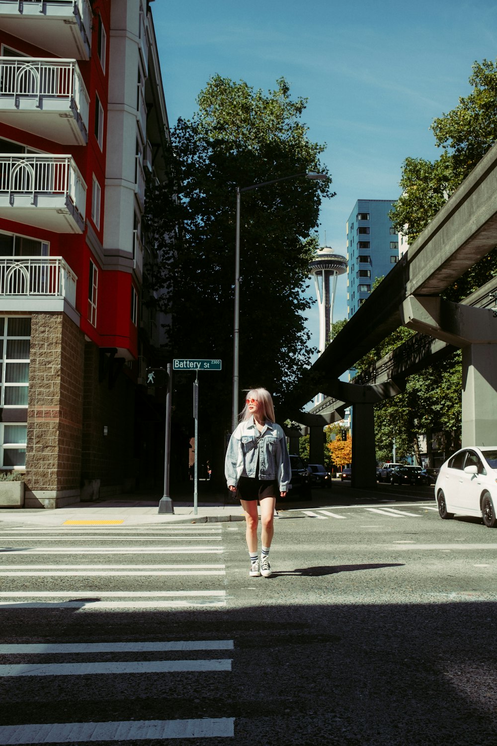 a woman walking across a street next to tall buildings