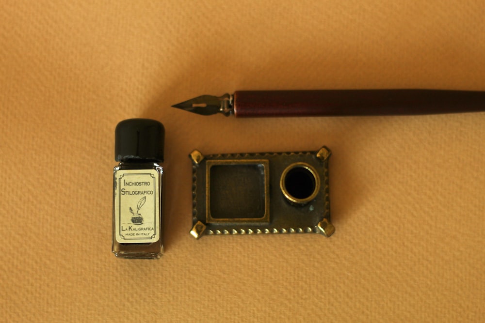 una penna, un flacone d'inchiostro e una fotocamera in miniatura su un tavolo