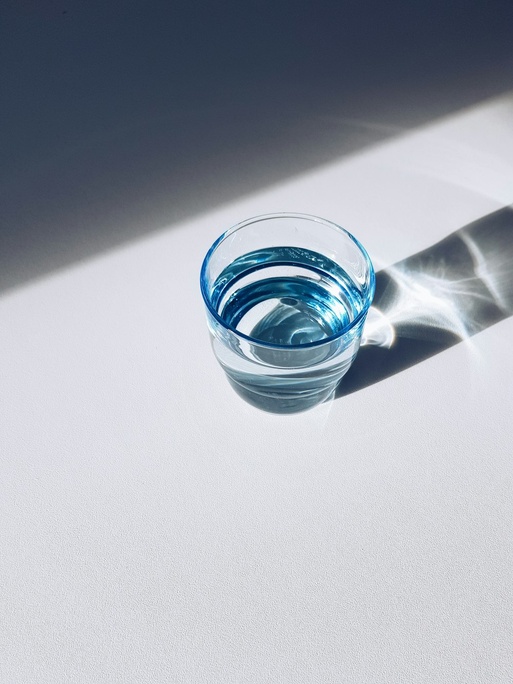 Un vaso de agua sentado encima de una mesa blanca