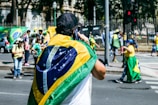 a man with a flag on his back walking down the street