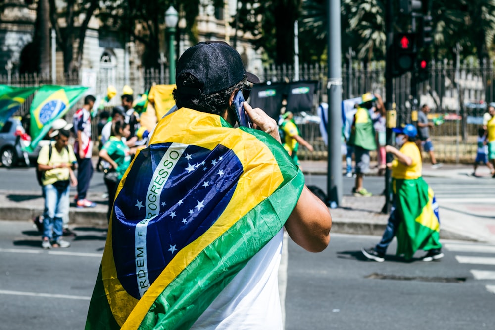 a man with a flag on his back walking down the street