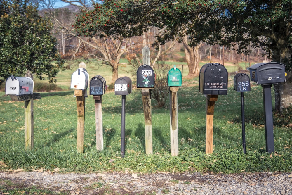 a row of mail boxes sitting on top of a lush green field