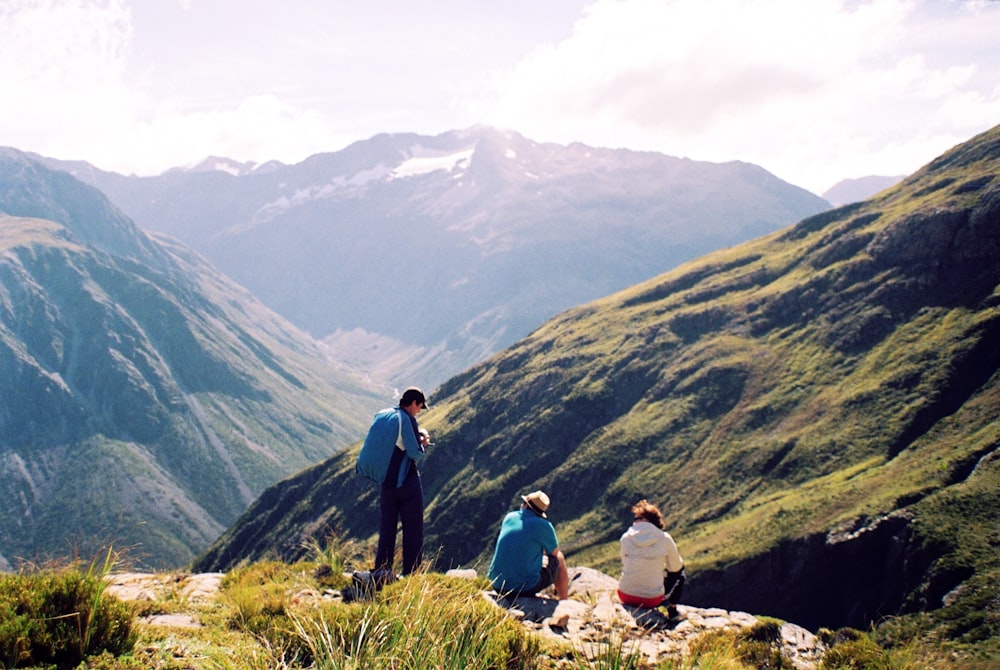 a group of people sitting on top of a lush green hillside