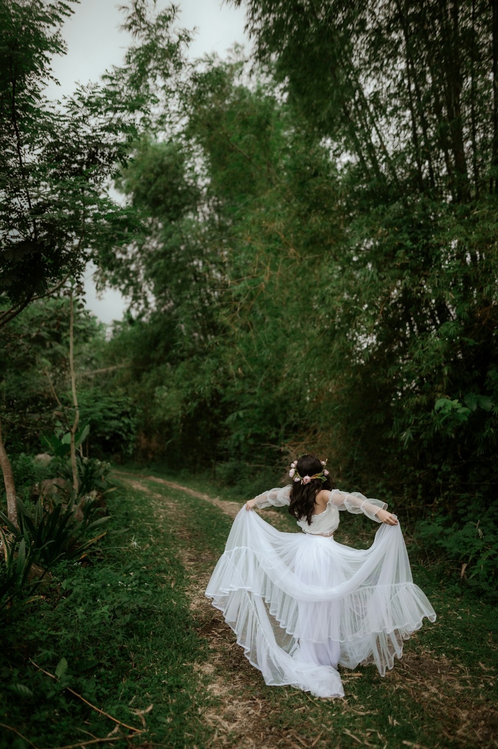 a woman in a white dress is walking through the woods