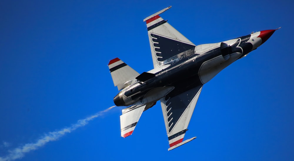 a fighter jet flying through a blue sky