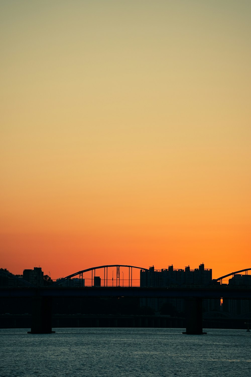 a plane flying over a bridge at sunset