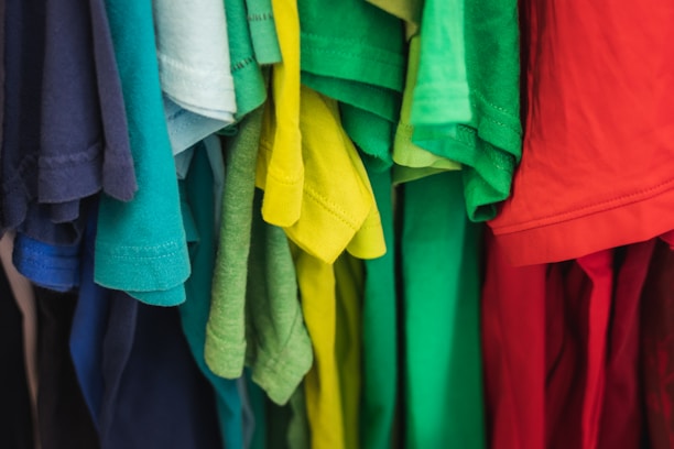 A collection of colorful t-shirts displayed on a wooden table.