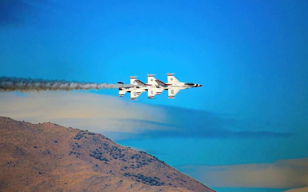 two jets flying in the sky near a mountain