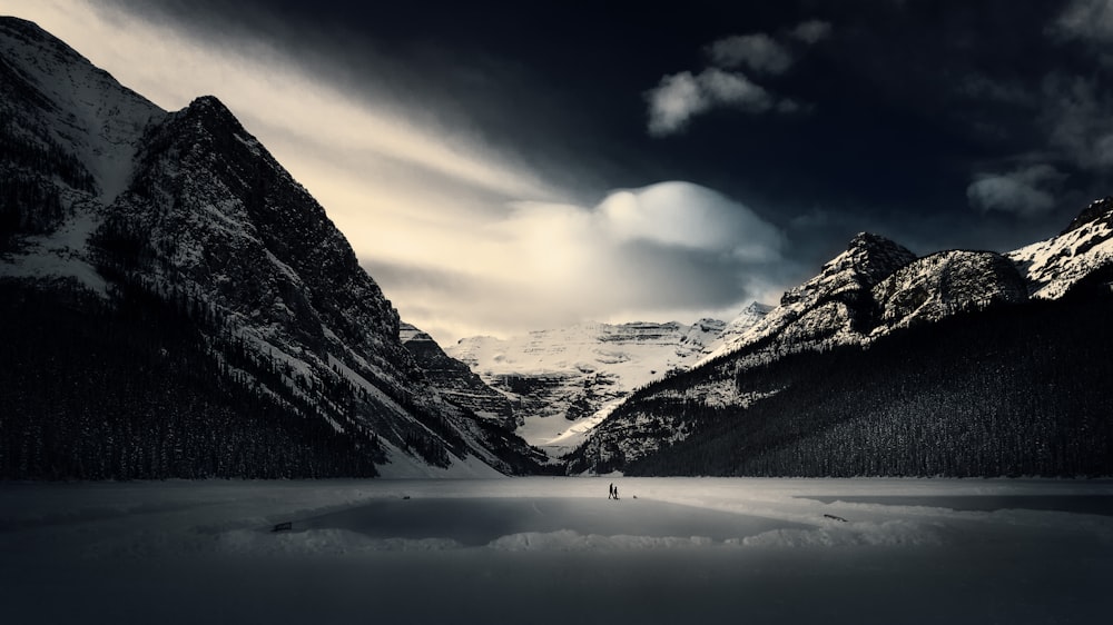 a person standing in the middle of a lake surrounded by mountains