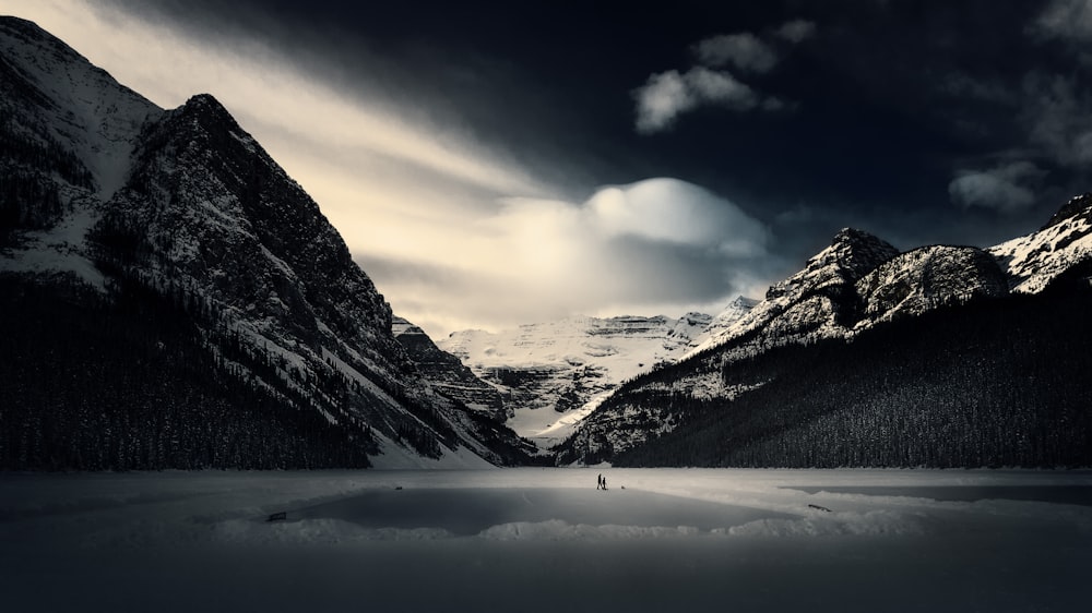 Una persona parada en medio de un lago rodeado de montañas