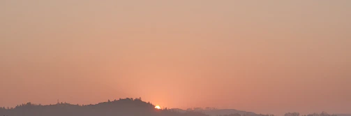 A serene landscape photo of a sunset over rolling hills with soft pastel colors.