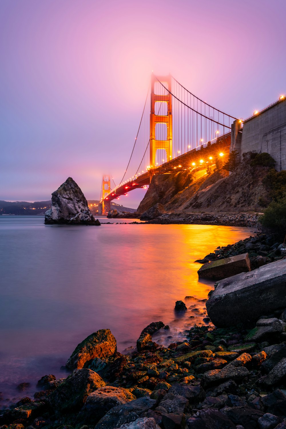 the golden gate bridge is lit up at night