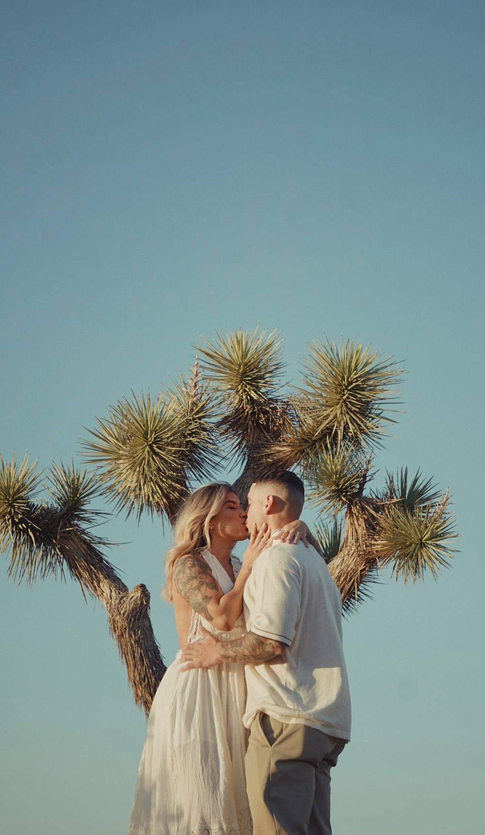 a man and a woman standing in front of a tree