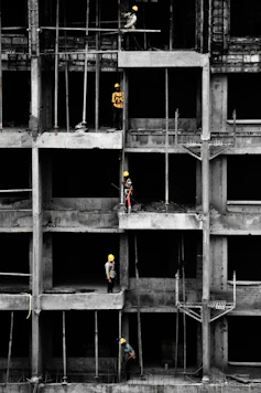 a group of men standing on top of a building under construction