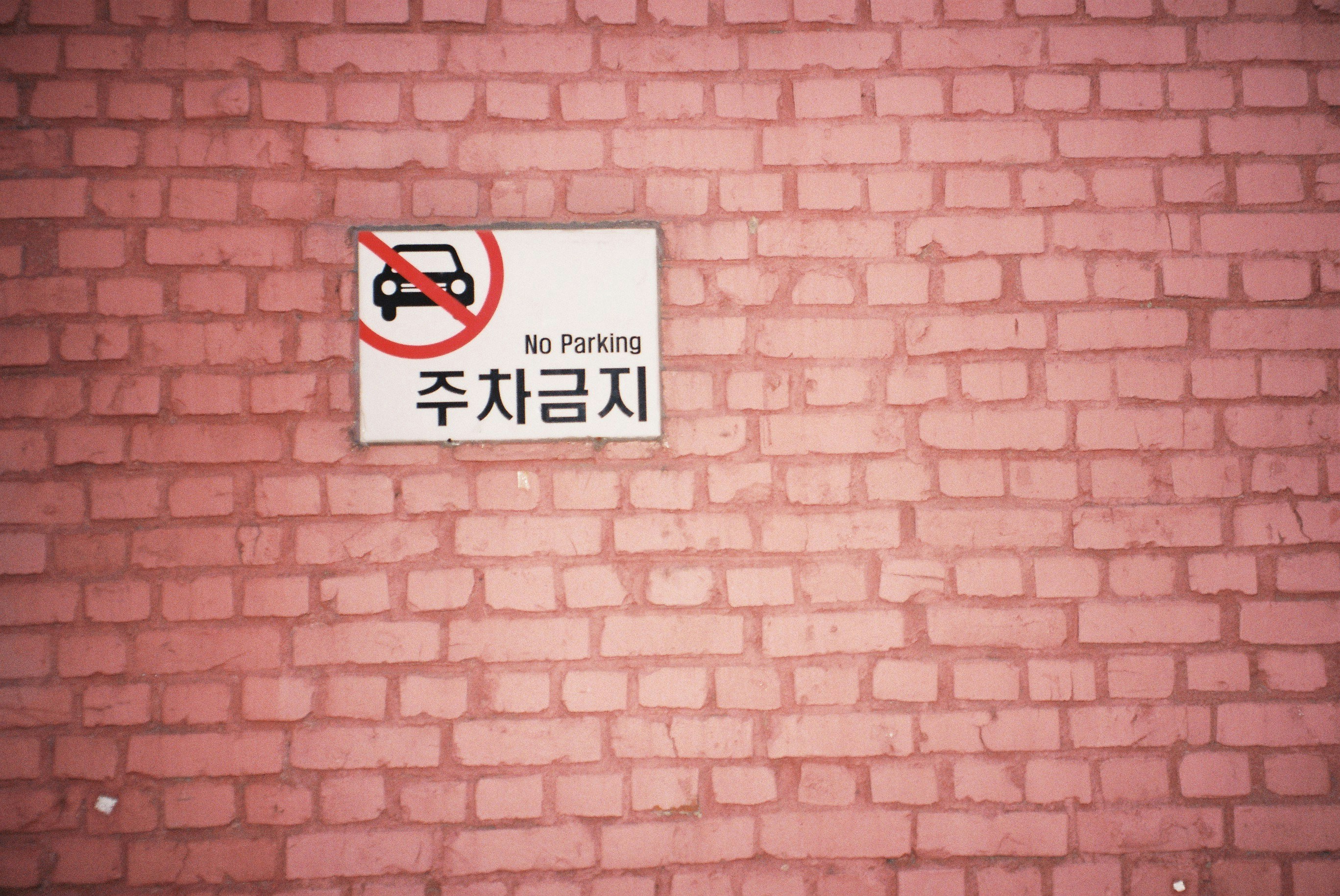 a no parking sign on a brick wall