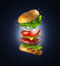 Animated layers of a classic hamburger assembling perfectly with fresh salad and a toasted bun.