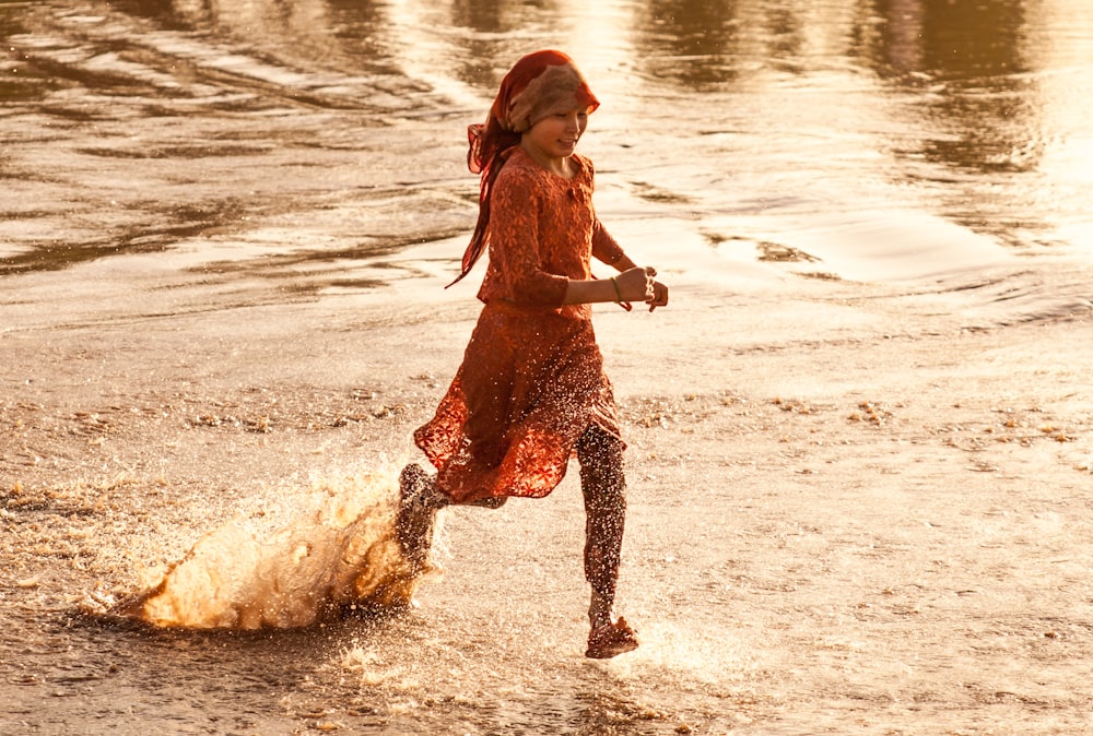 a girl in a red dress is playing in the water