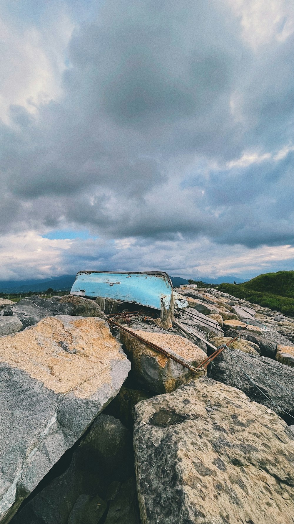 a blue boat sitting on top of a pile of rocks