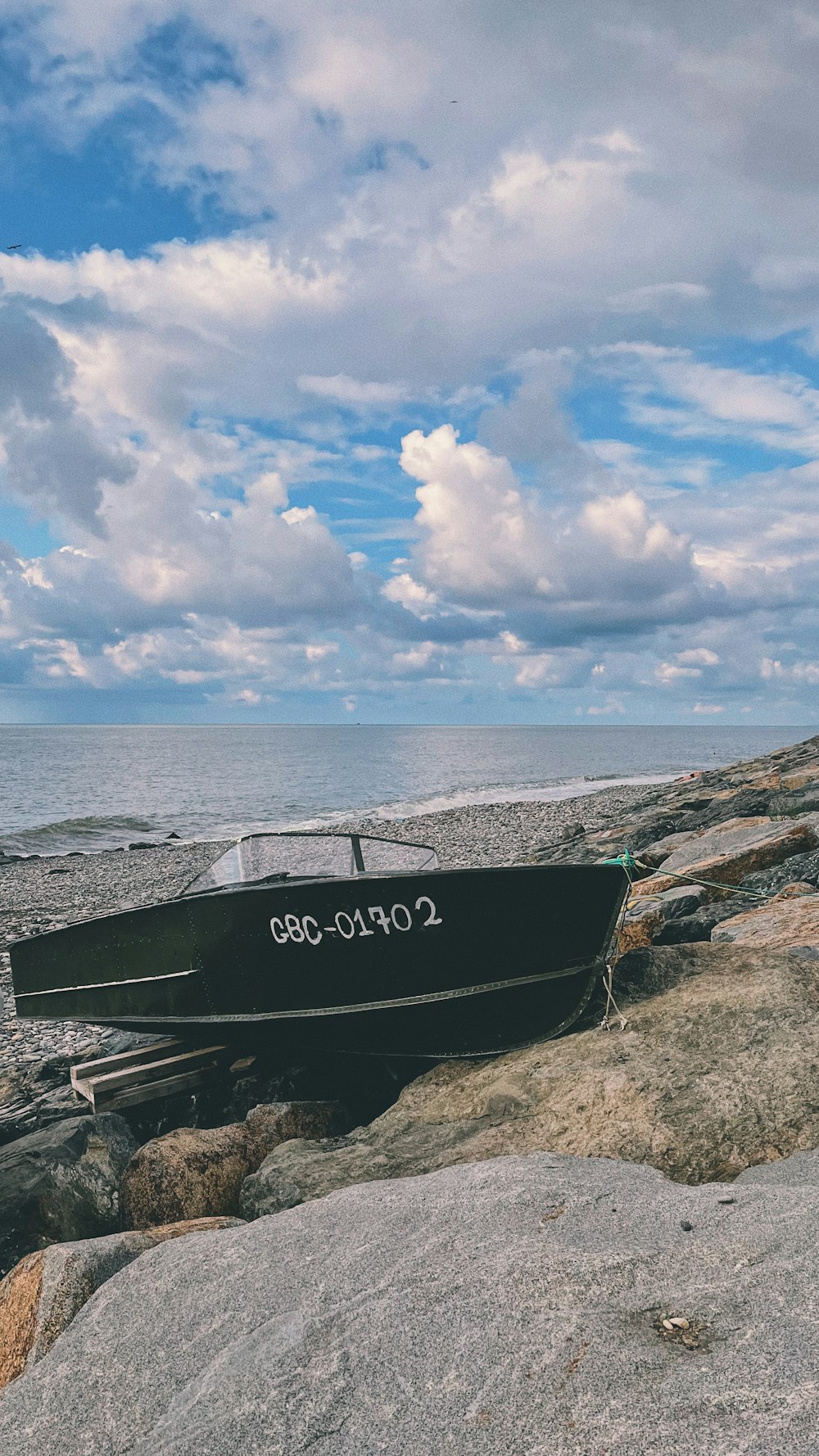 a black boat sitting on top of a rocky beach