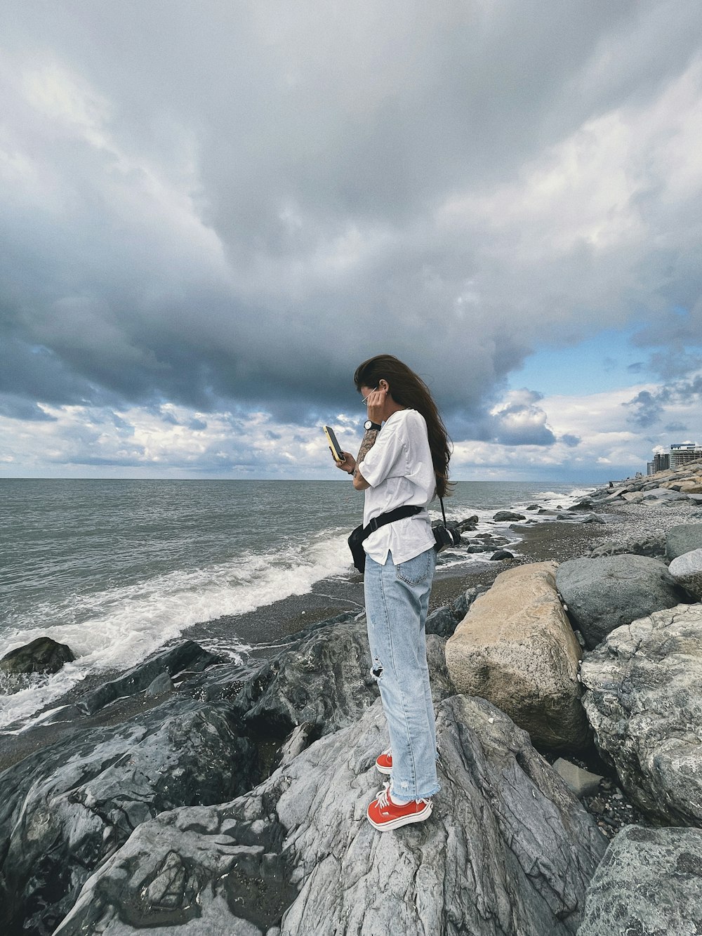 a woman standing on rocks looking at her cell phone