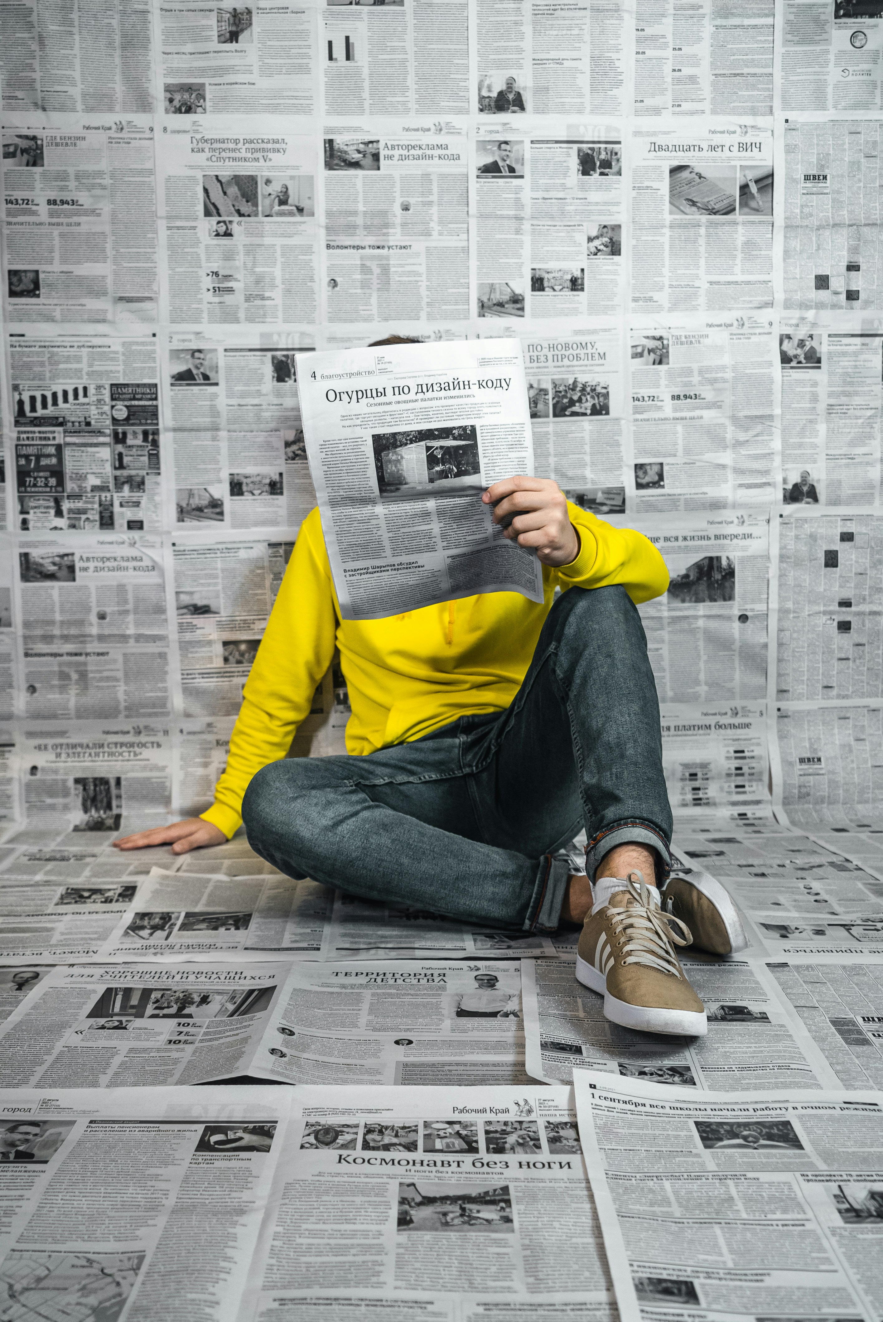 a man sitting on the floor reading a newspaper