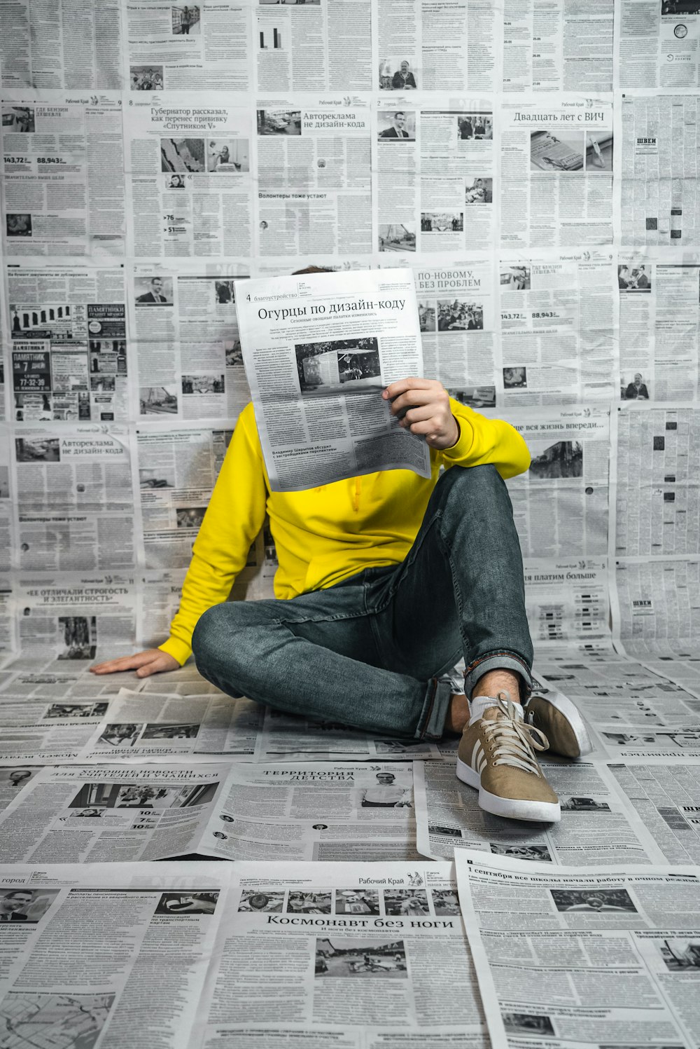 a man sitting on the floor reading a newspaper
