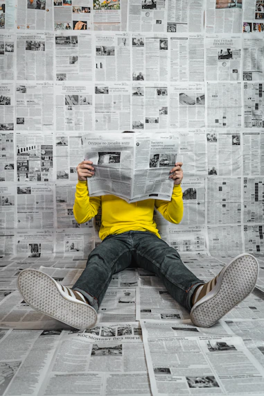 a person sitting on the floor reading a newspaper