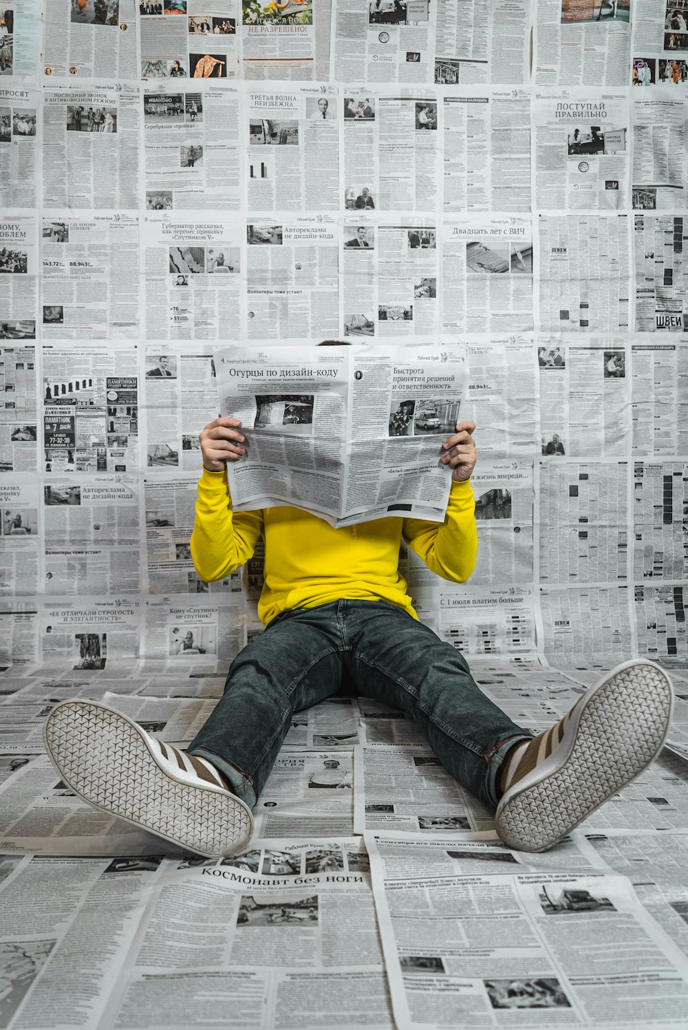 Una persona sentada en el suelo leyendo un periódico