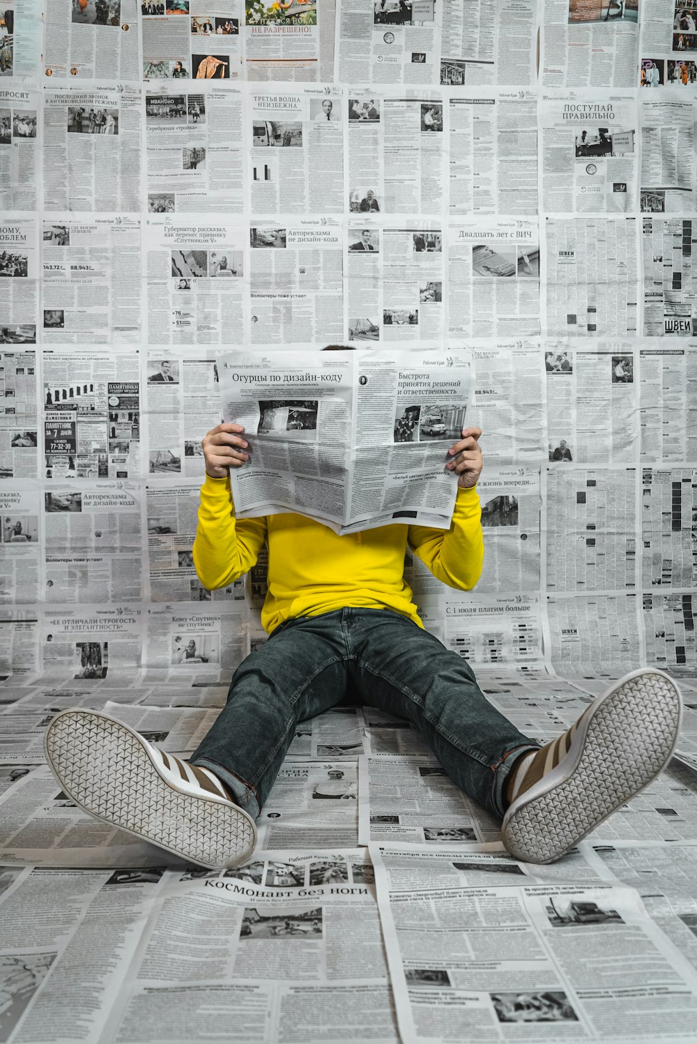 a person sitting on the floor reading a newspaper