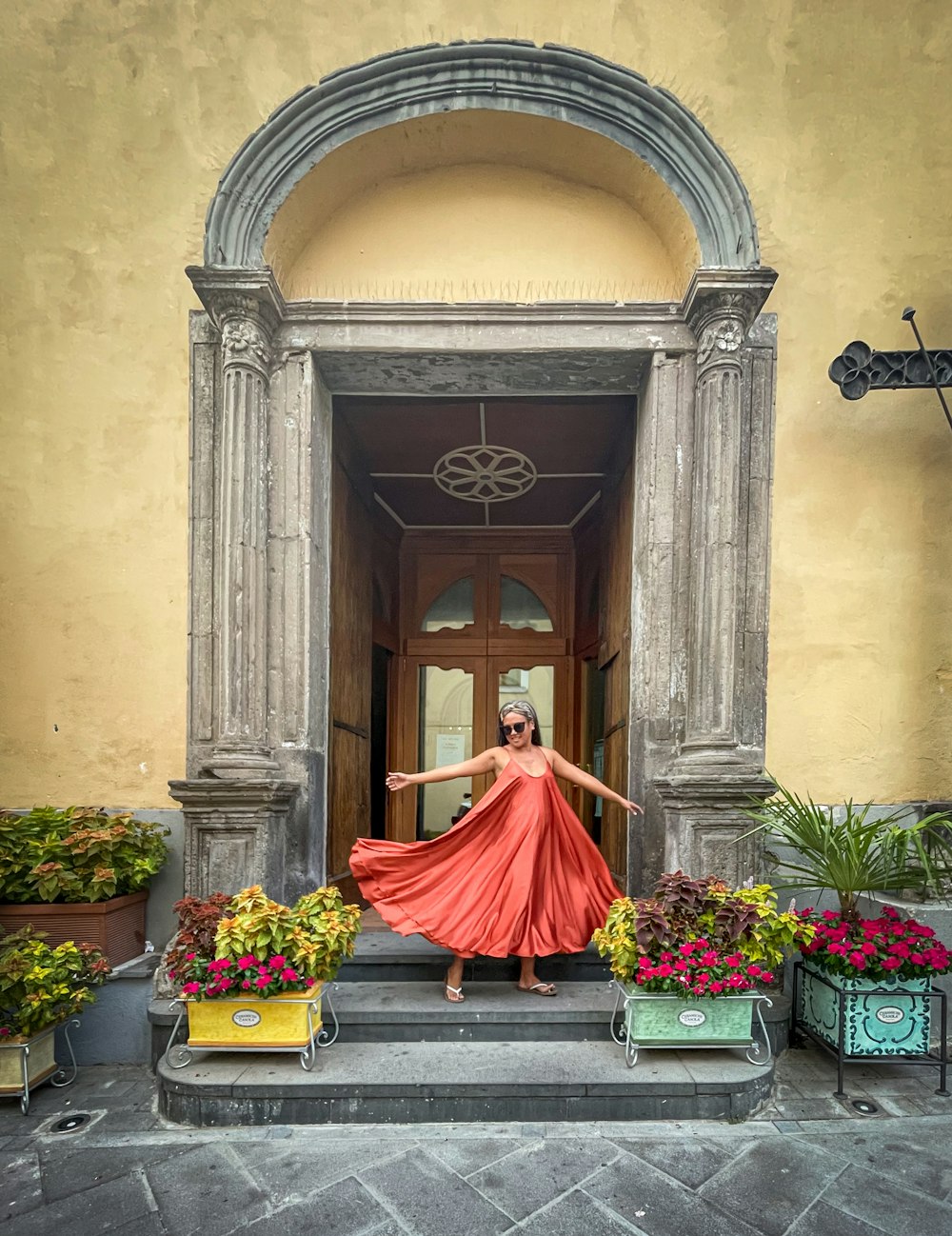 a woman in a red dress is standing on the steps of a building