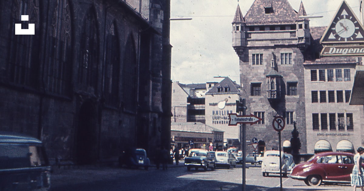 An old photo of a city street with a clock tower in the background An old photo of a city street with a clock tower in the background