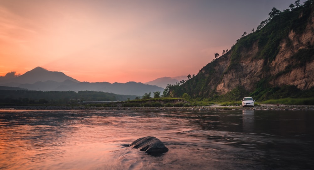 a van is driving down a river at sunset