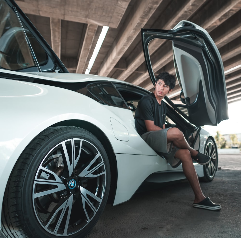 a man sitting on the door of a white car