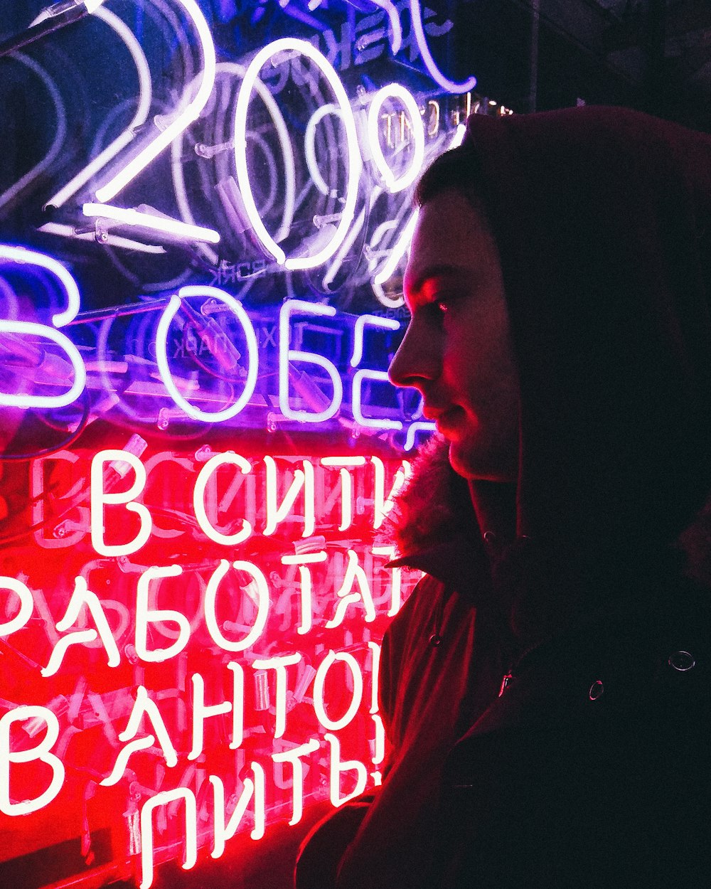 a person standing in front of a neon sign