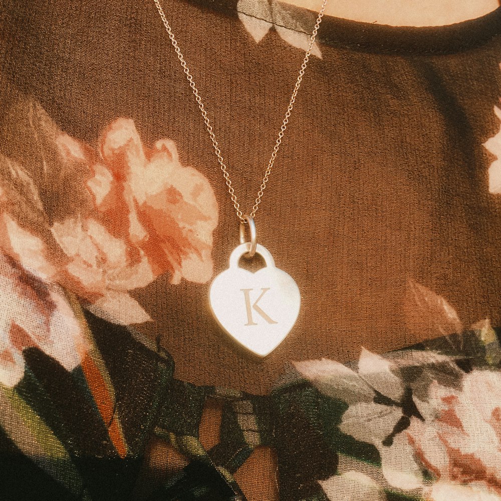 a woman wearing a necklace with a heart shaped pendant