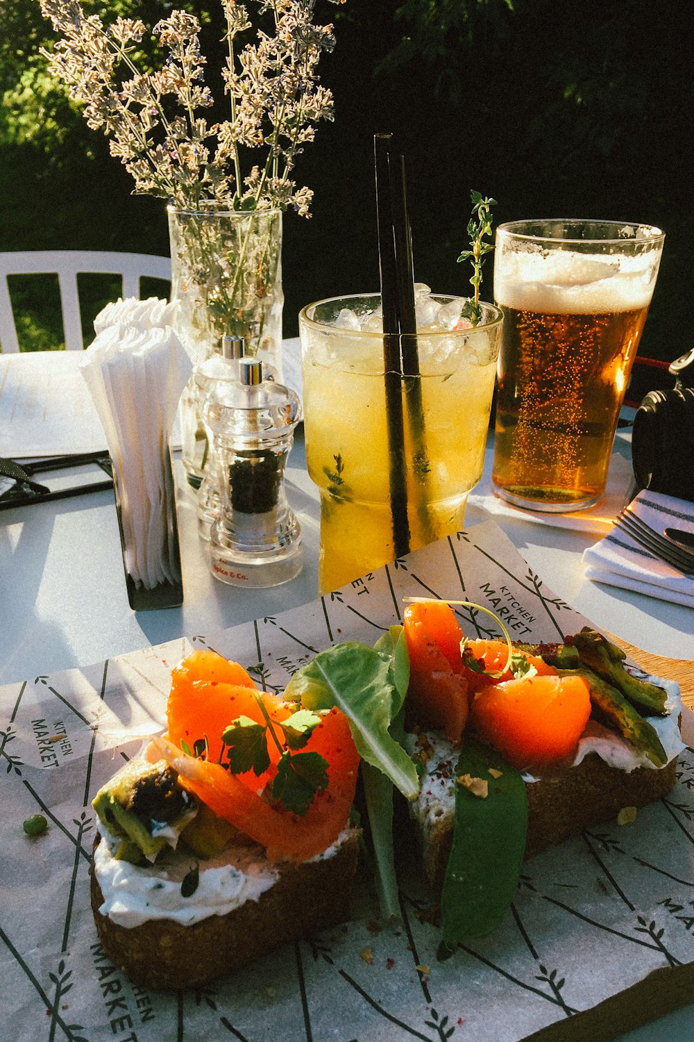 a table topped with a cut in half sandwich next to a glass of beer