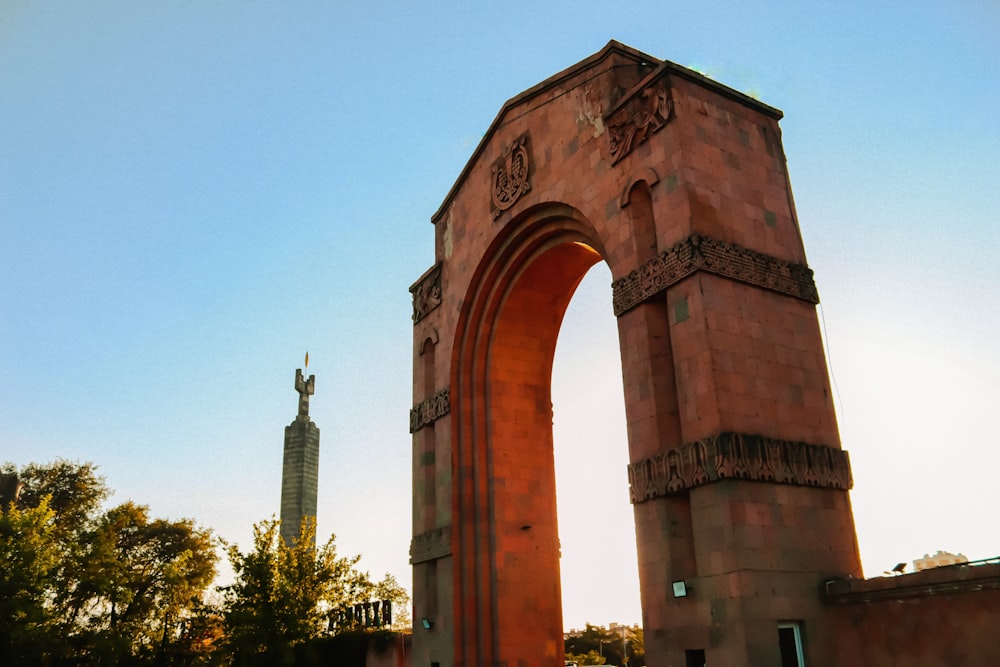 a tall red brick arch with a statue in the background
