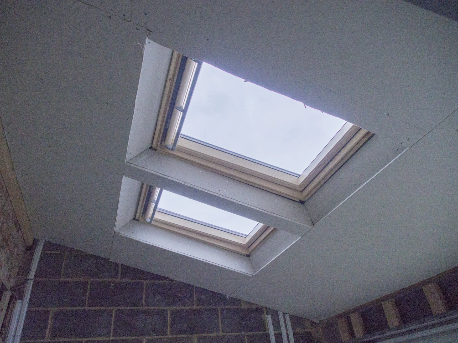 a room with a skylight and a brick wall