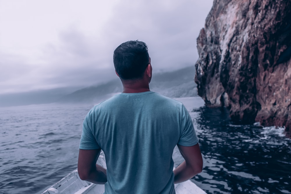 um homem sentado em um barco olhando para o oceano