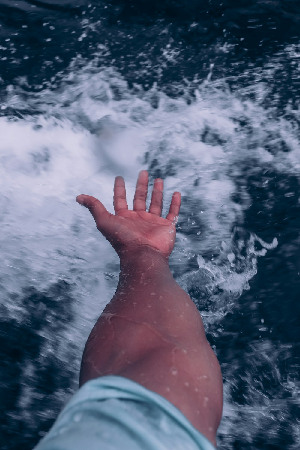 a person's hand reaching for something in the water