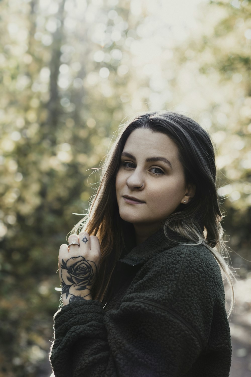 a woman with a tattoo on her arm standing in the woods