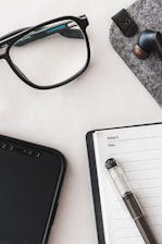 A neatly arranged workspace featuring a smartphone, wireless earbuds, and a laptop, highlighting tech accessories.