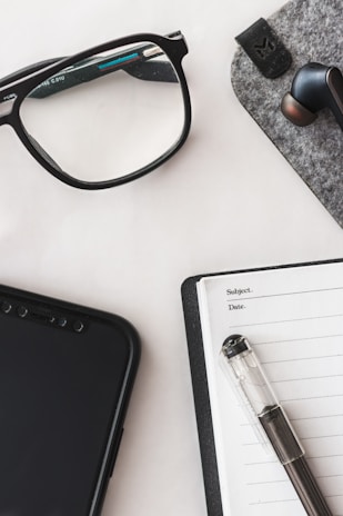 A neatly arranged workspace featuring a smartphone, wireless earbuds, and a laptop, highlighting tech accessories.