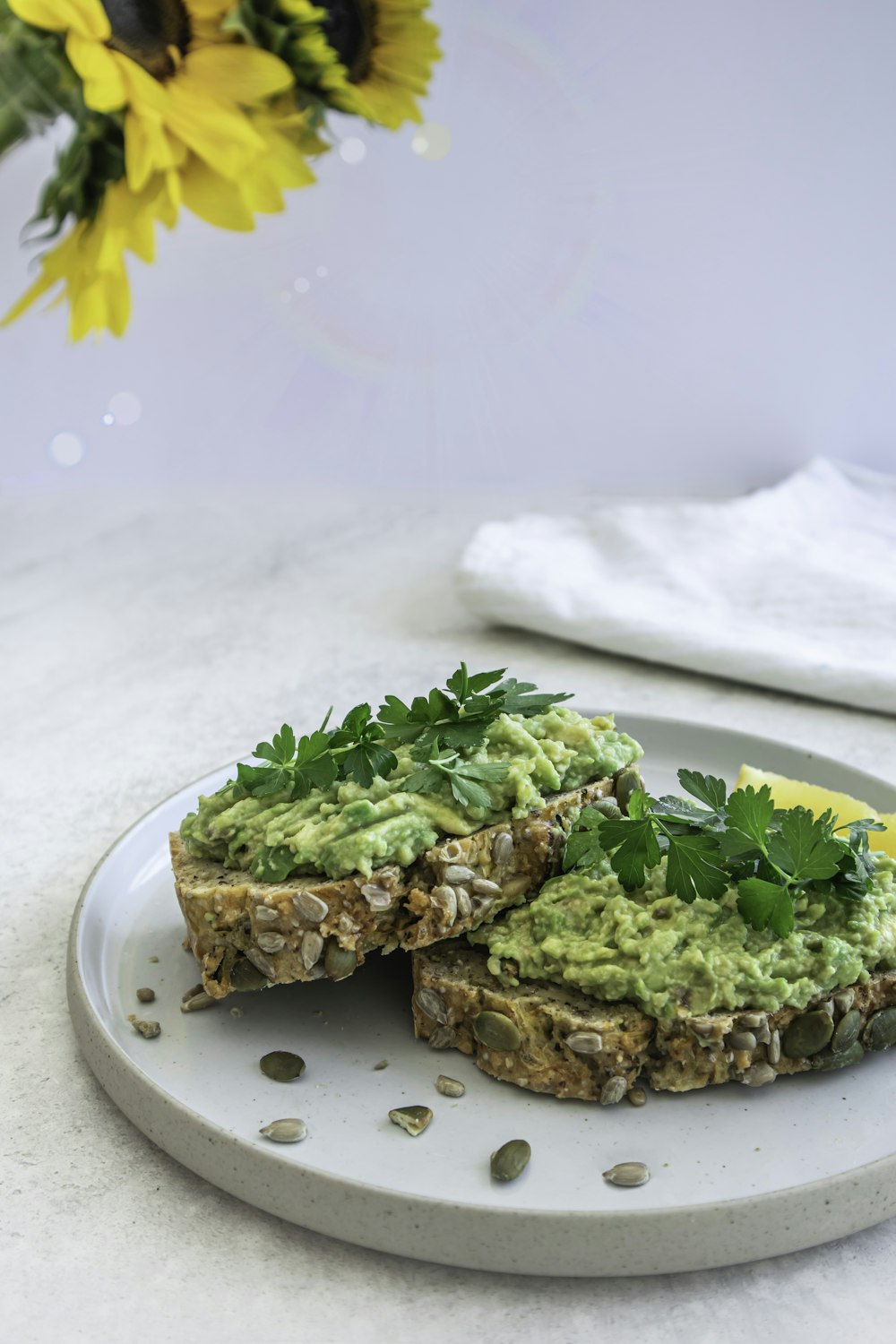 une assiette blanche garnie d’un sandwich recouvert de guacamole